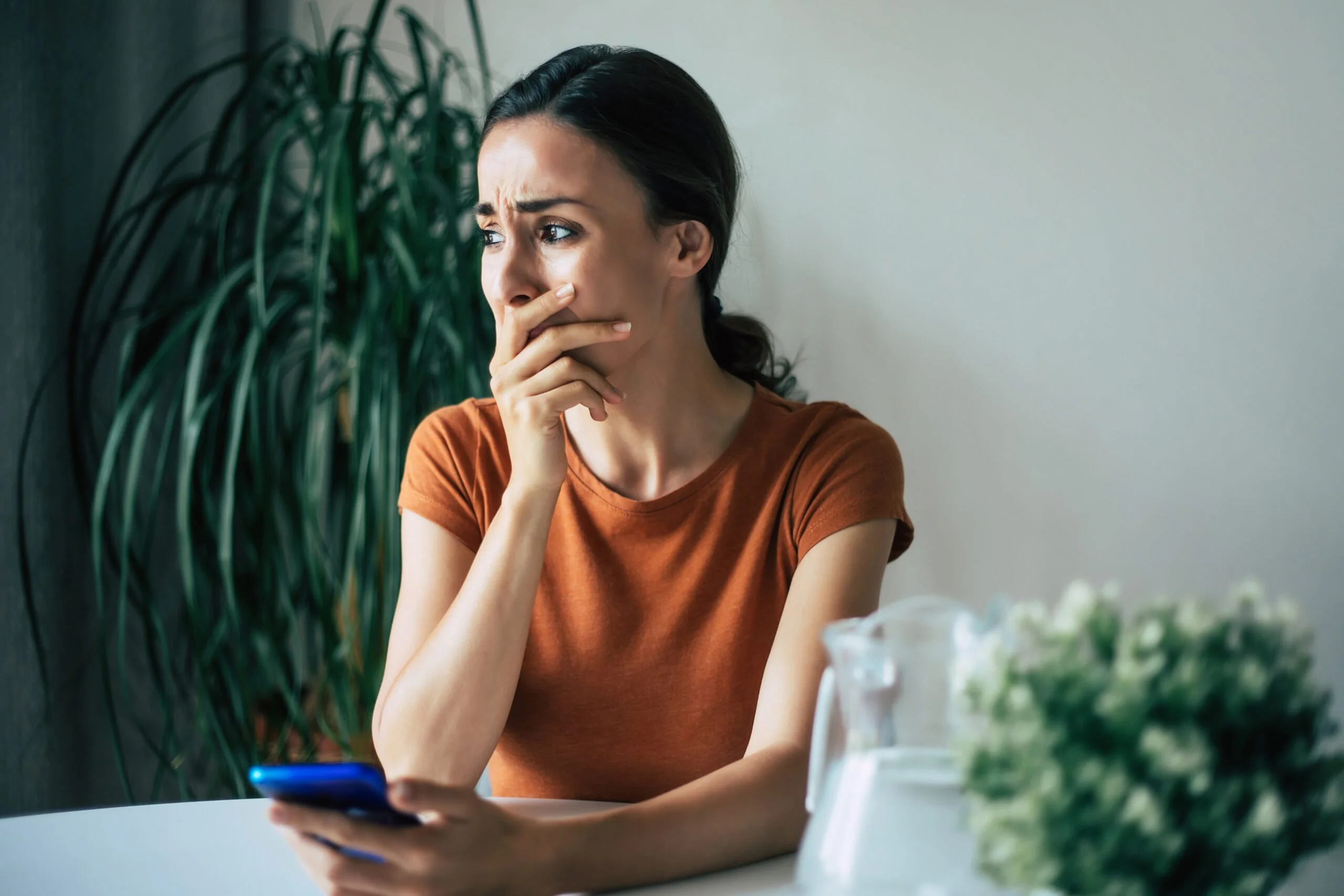 A young woman in tears holds a cell | Source: Shutterstock
